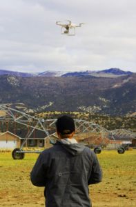 A Snow College agriculture student uses a drone to check the dispersal of water from GPS-controlled sprinkler heads on a center pivot irrigation system.