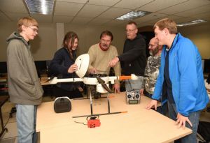 Bill Judycki, professor of Remotely Piloted Aircraft Systems (RPAS) at Mohawk Valley Community College, shows several students the inner components of one of the college’s drones while student Annie Born holds the quad copter’s cap