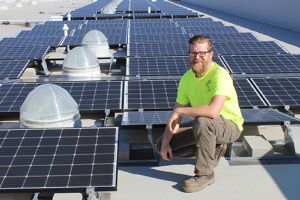 student installing solar panels on top of Energy Building