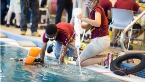 An image from the ATE Impacts book,. The image shows two students preparing their underwater robot in a pool