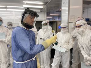 An instructor holds up an etched wafer for students to examine in a NanoSystems Institute cleanroom.